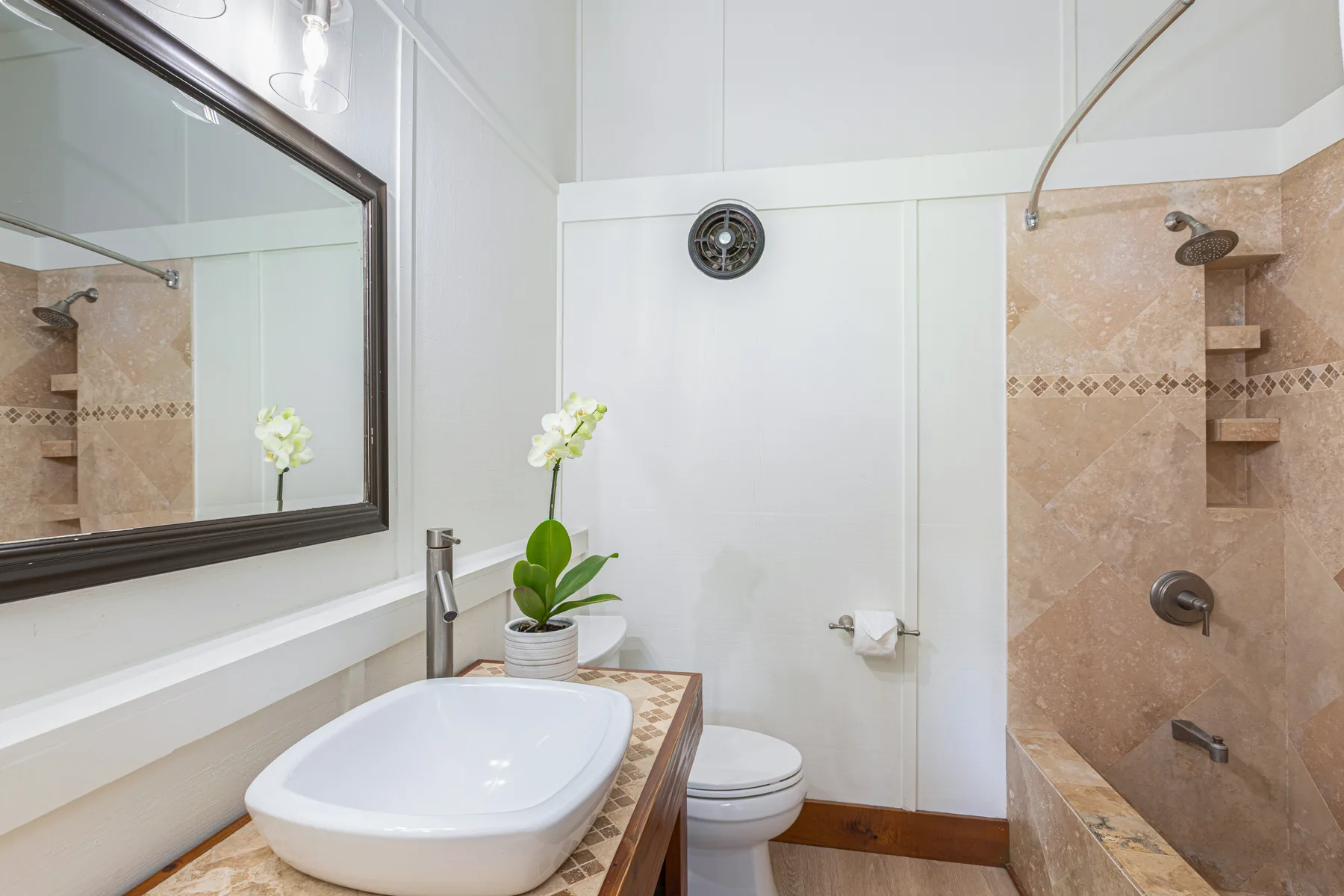 A bathroom with a sink, toilet, and tiled shower area.