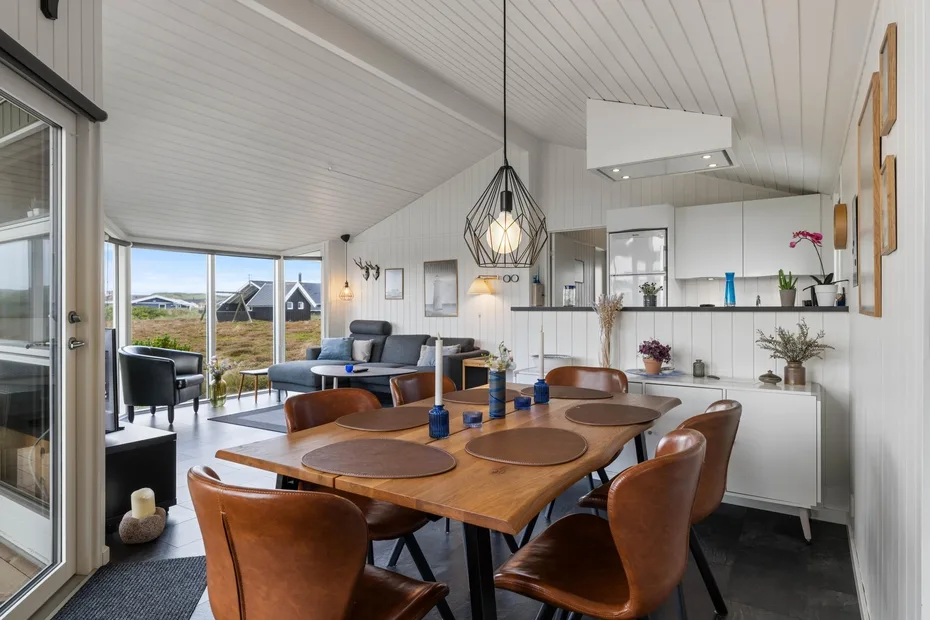 Comedor con una mesa de madera y una sala de estar visible al fondo.