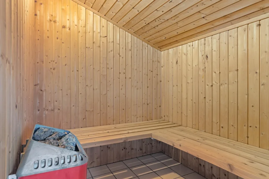 Una sauna revestida de madera con bancos en L y un calentador.