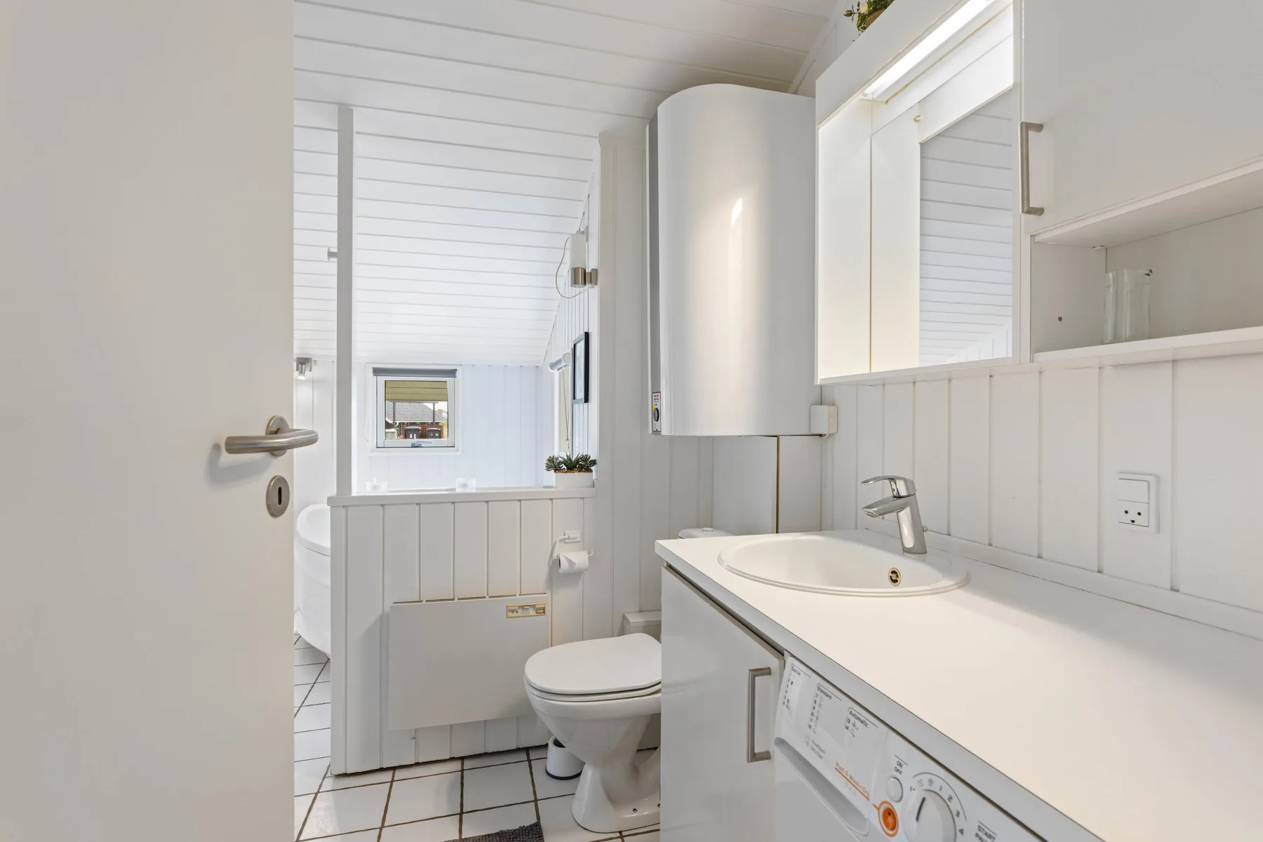 Un baño luminoso con lavabo, espejo e inodoro.