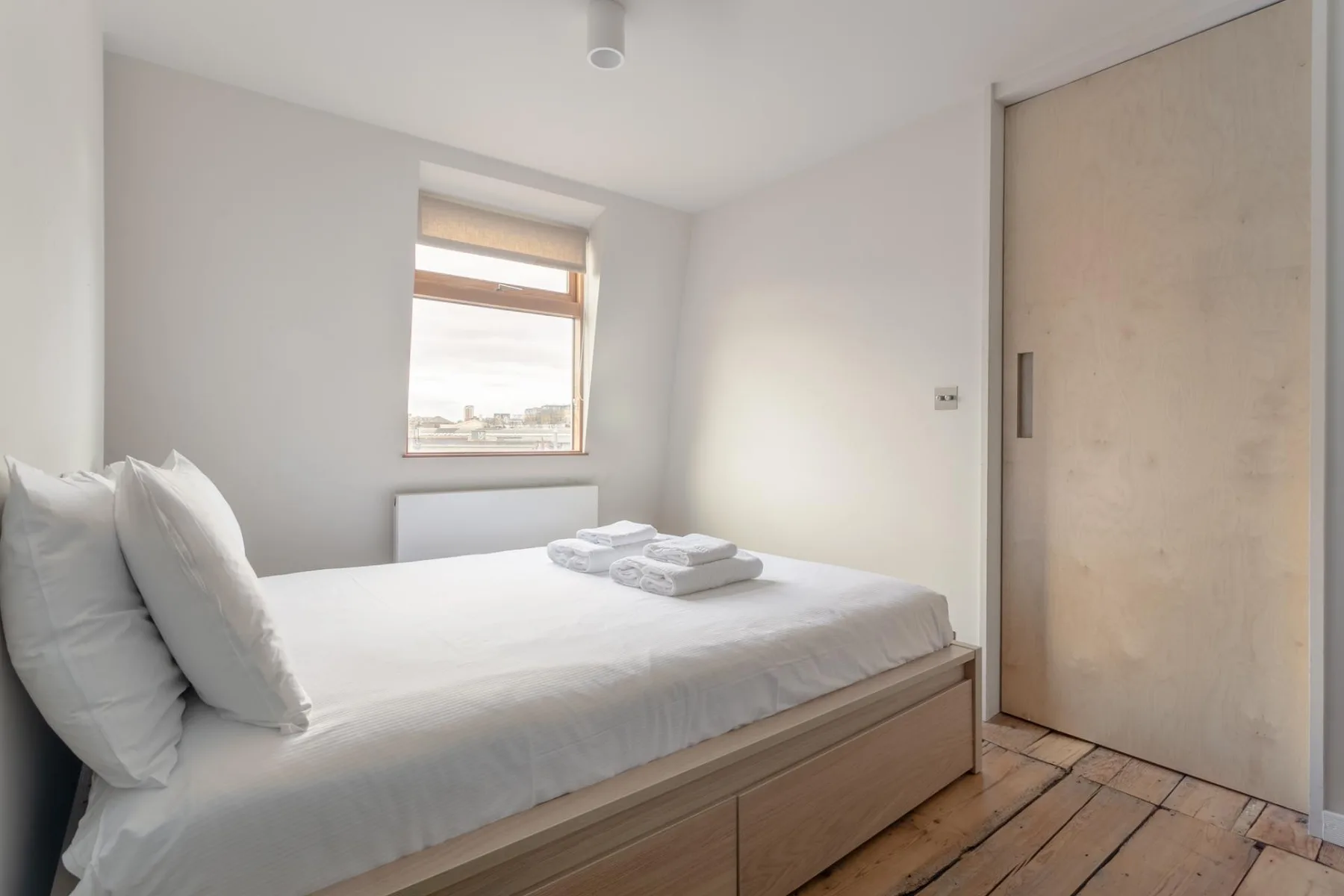 A bright bedroom with a bed, a window, and a sliding door.
