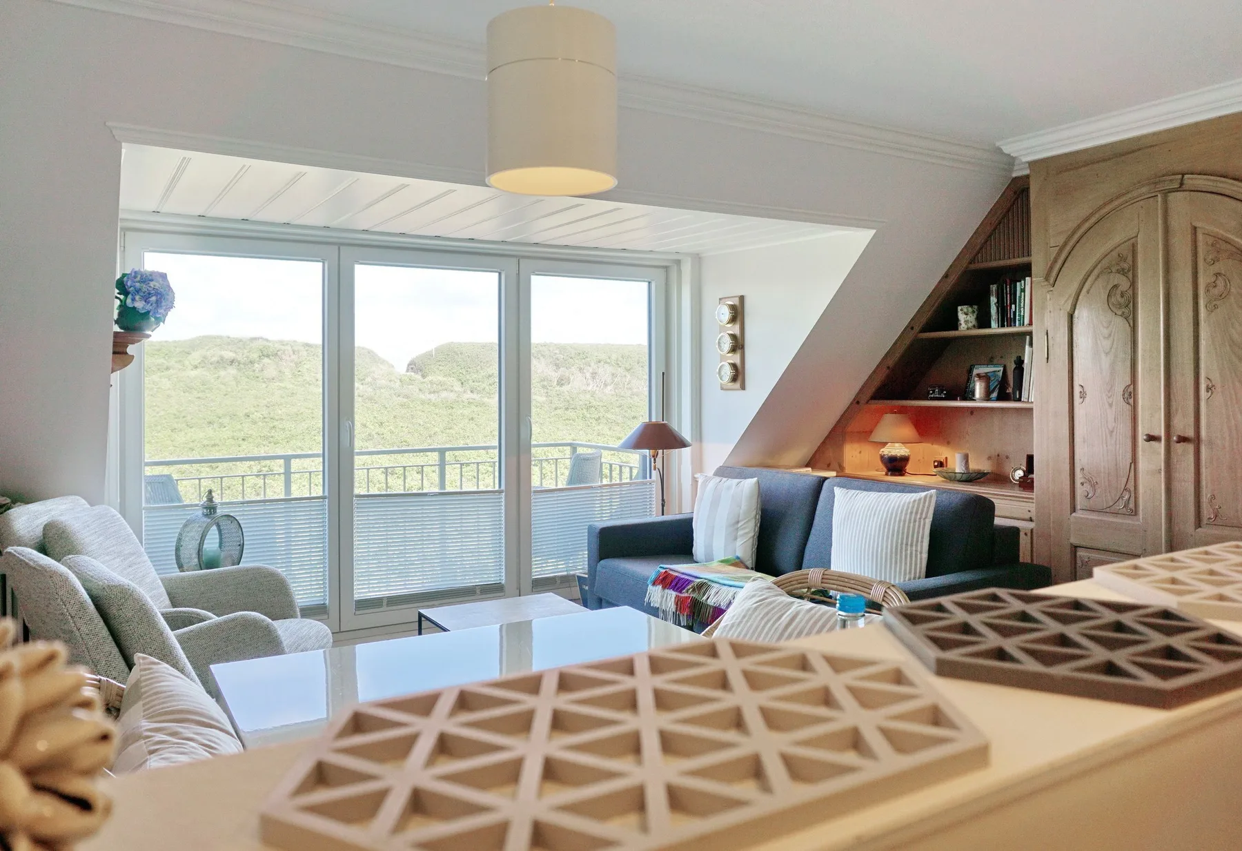 Una sala luminosa con asientos junto a amplias ventanas con vistas a colinas verdes.
