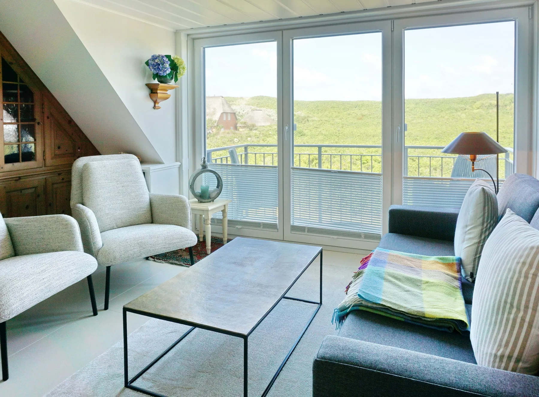 Una sala luminosa con asientos y grandes ventanas con vistas a un paisaje cubierto de hierba.