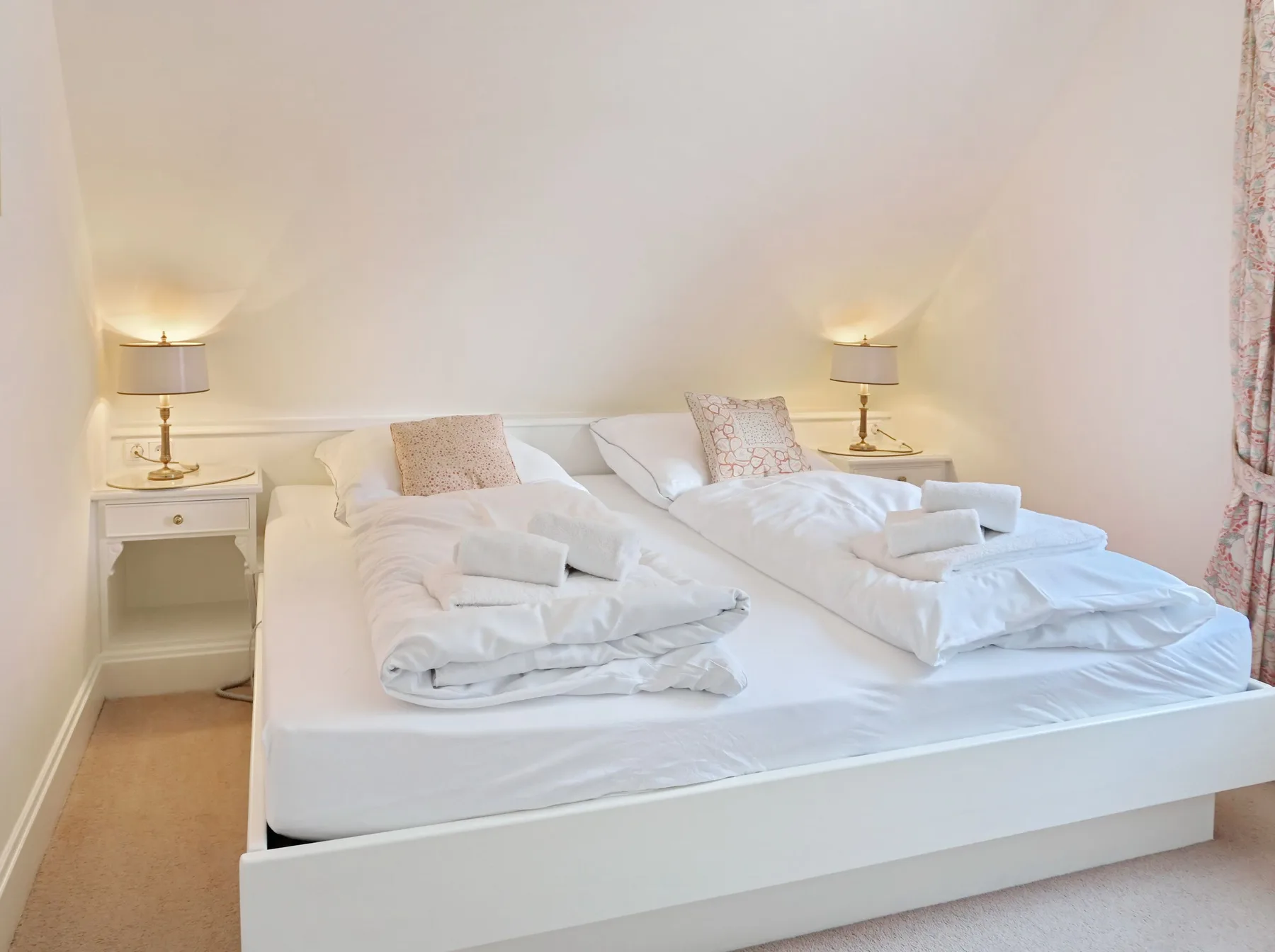 Un dormitorio con una cama grande, ropa de cama blanca y lámparas de mesilla a juego.