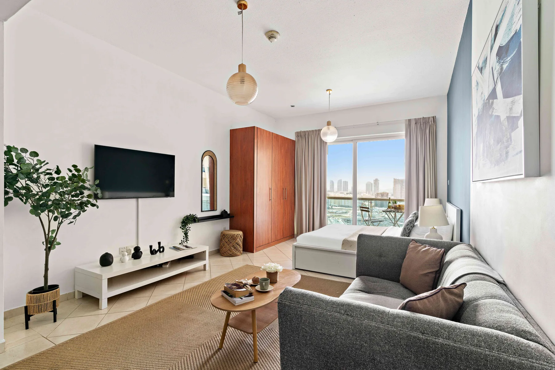 Una sala de estar con televisor, asientos y una ventana grande con vistas a la ciudad.