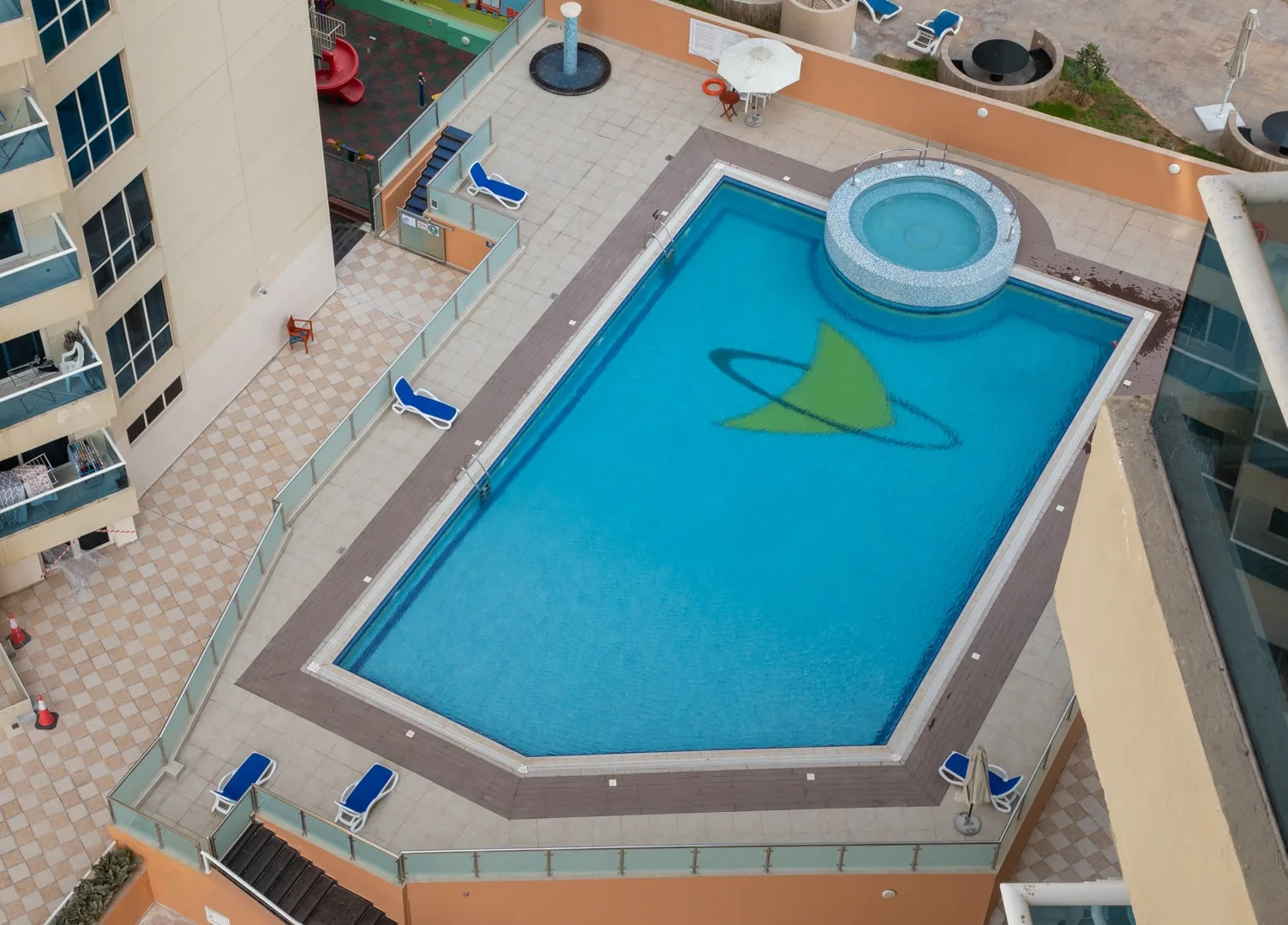 Una piscina al aire libre con una sección circular elevada y un diseño verde en el agua.