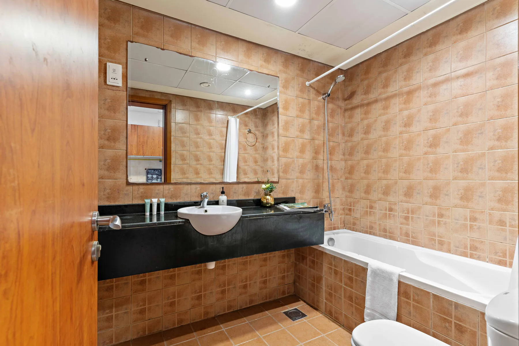 Un baño con azulejos, bañera, ducha y lavabo bajo un espejo grande.
