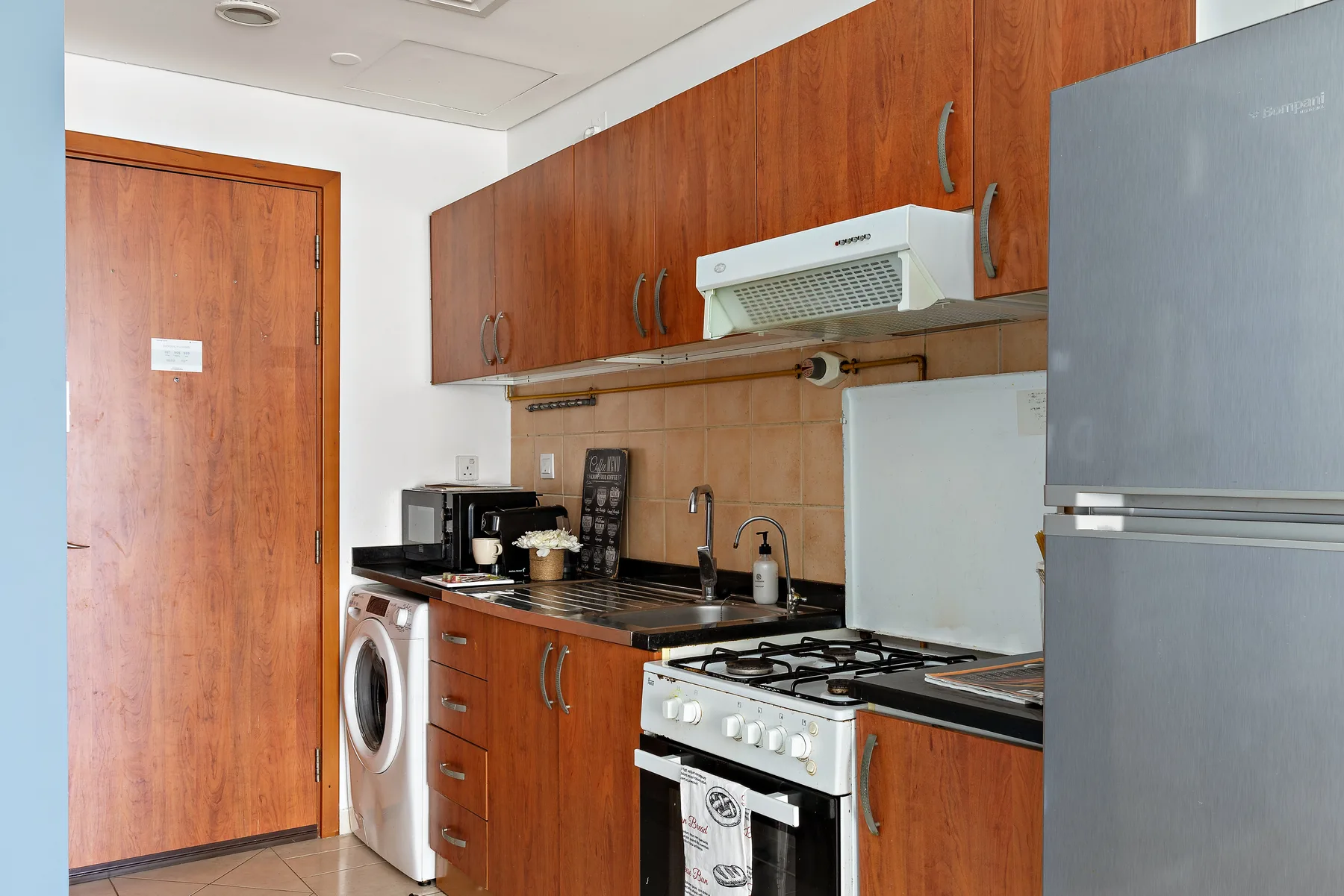 Una cocina compacta con gabinetes de madera, una estufa y un refrigerador.