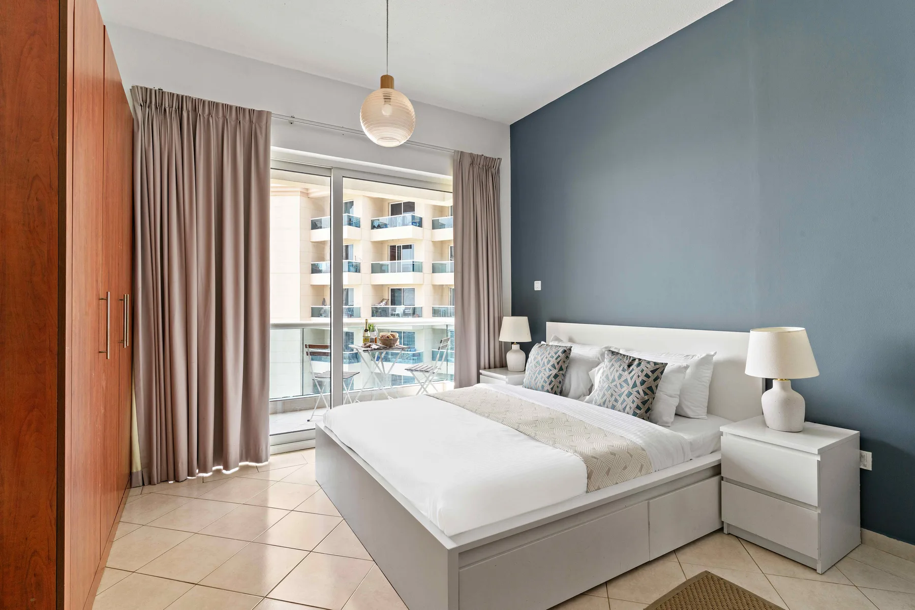 Un dormitorio con una cama grande, mesitas de noche y cortinas junto a la ventana.