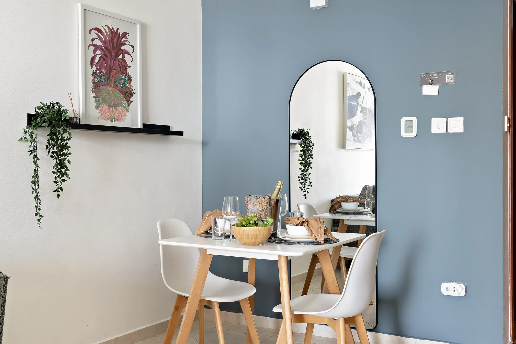 Comedor con una mesa y sillas junto a una pared azul y un espejo.