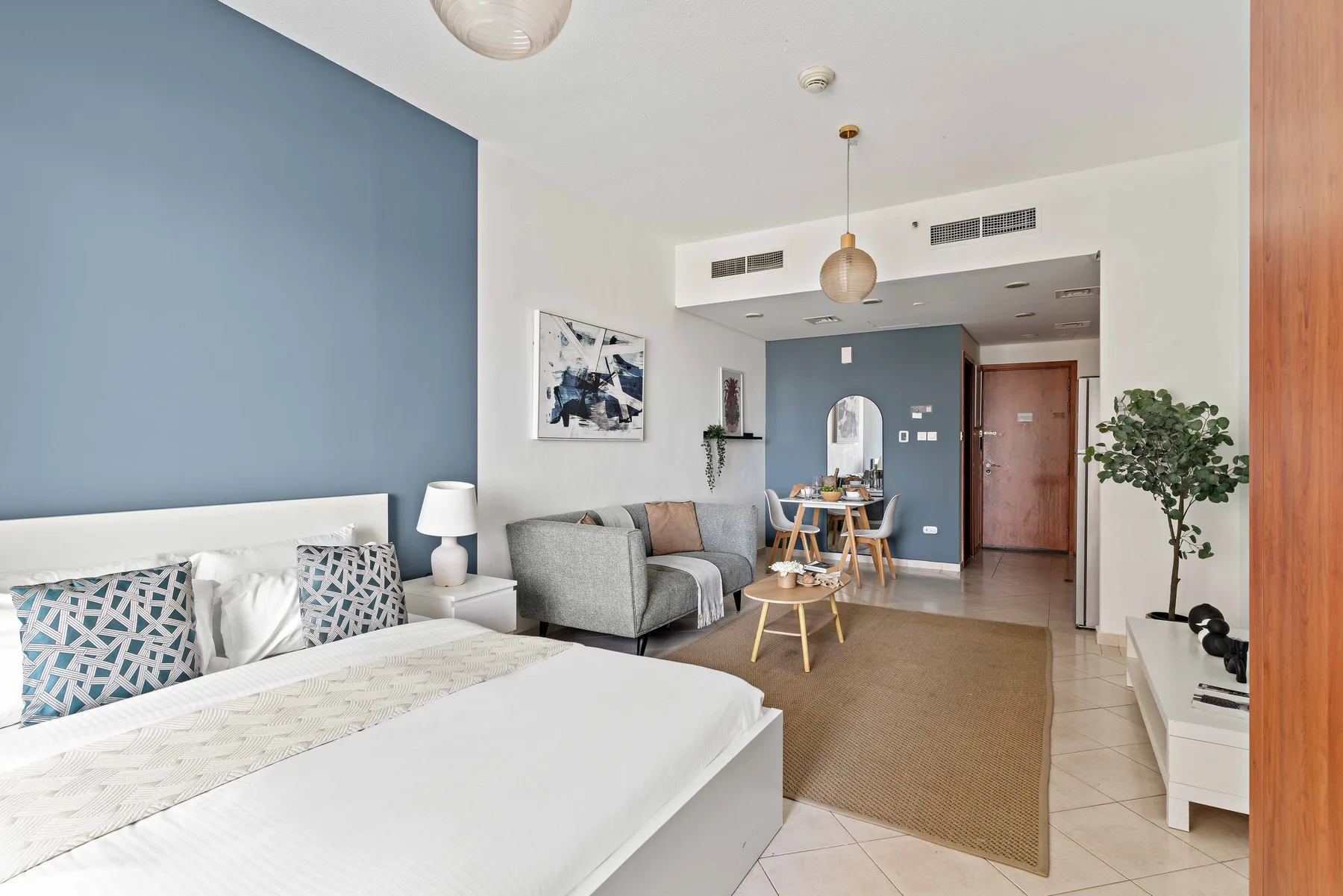 Un dormitorio con cama, zona de estar y una pared azul.