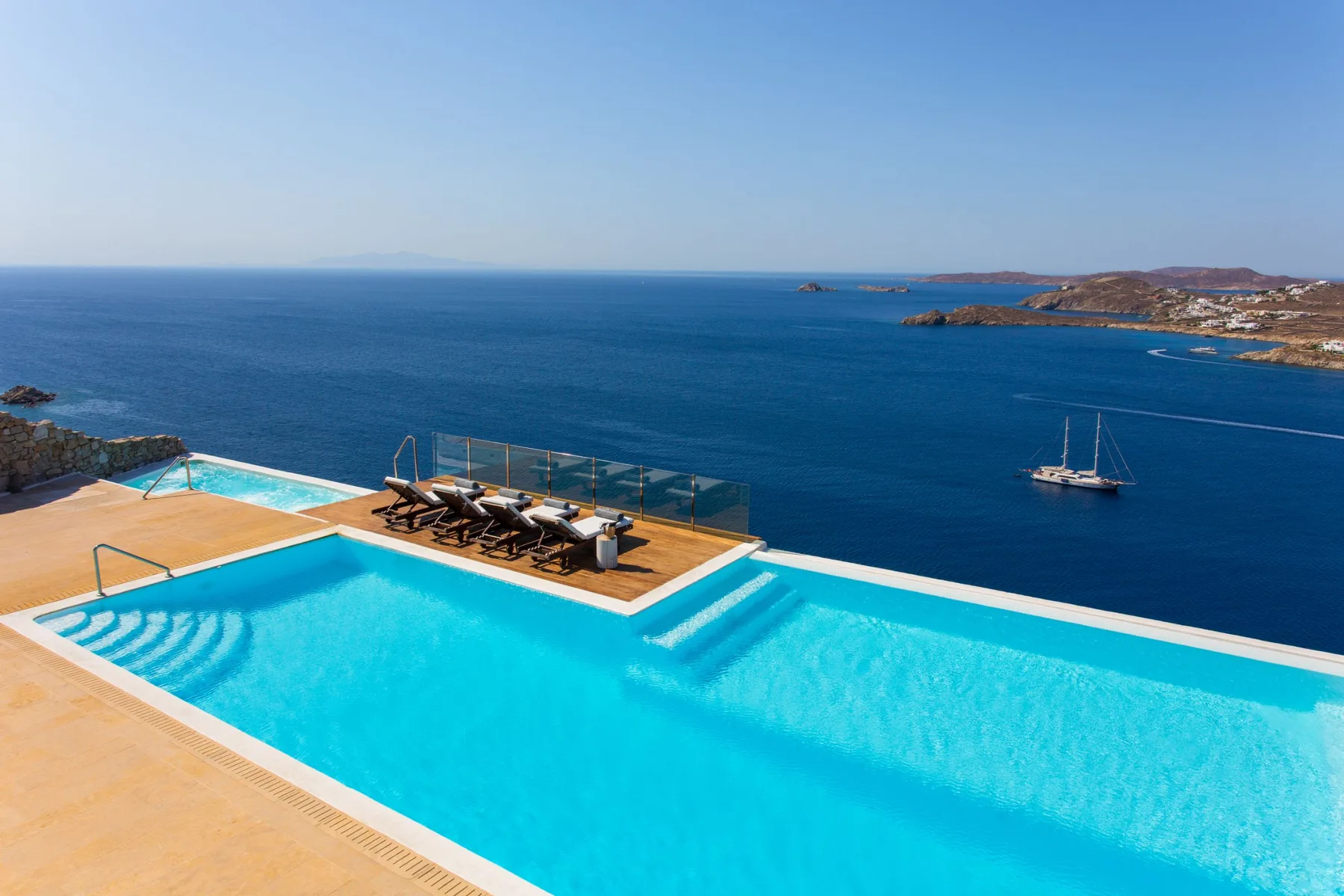Una piscina al aire libre da al mar, con tumbonas junto al agua.