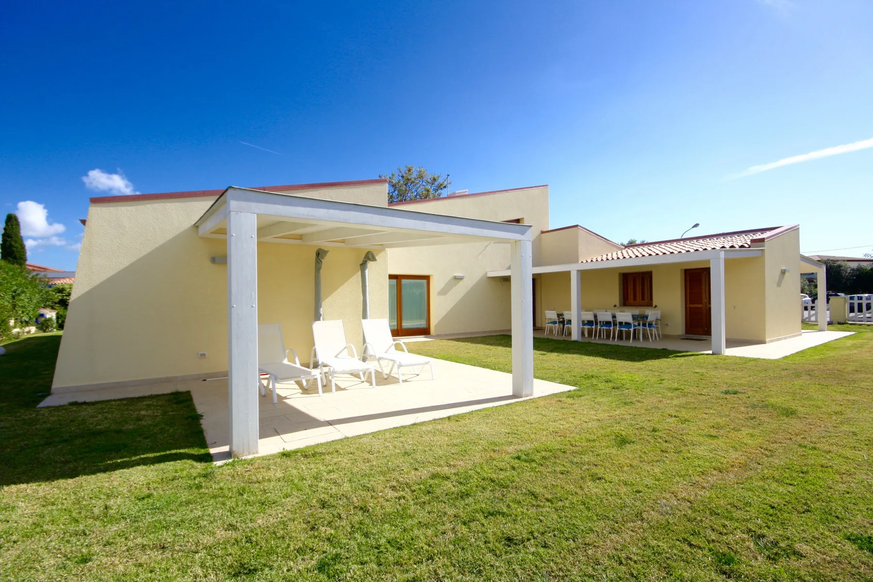 Una casa moderna da a un patio cubierto con asientos al aire libre y césped.