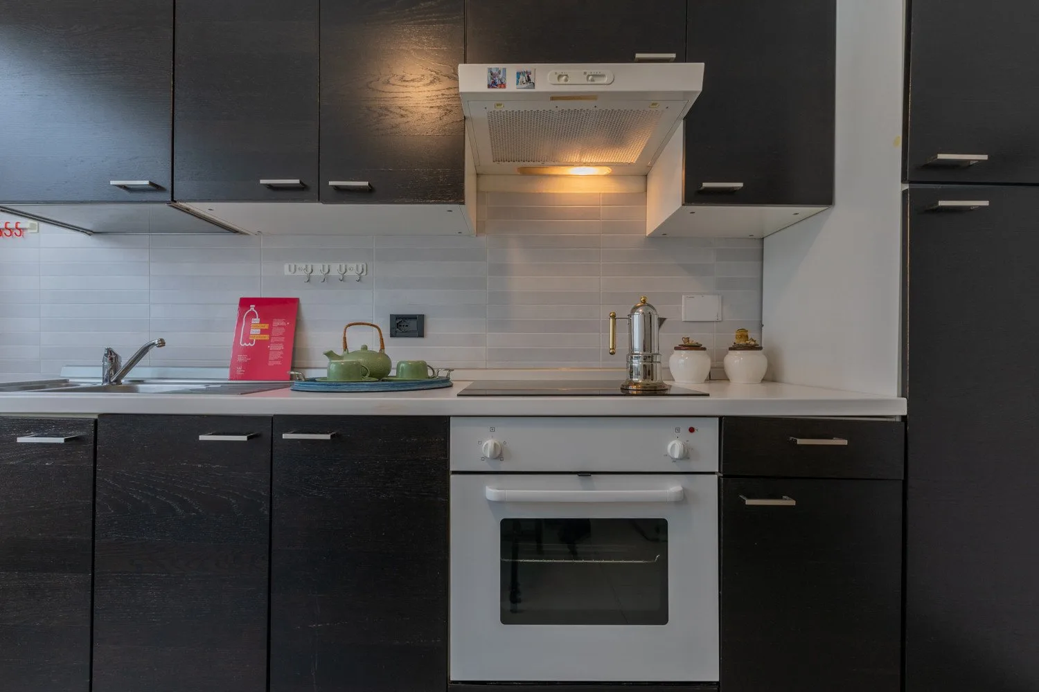 Una cocina moderna con gabinetes oscuros, una encimera y un horno empotrado.