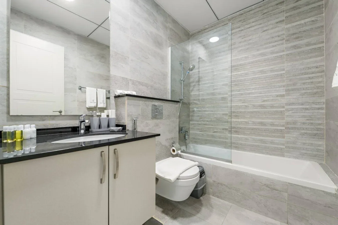 Un baño revestido de azulejos con lavabo, inodoro y bañera con ducha.