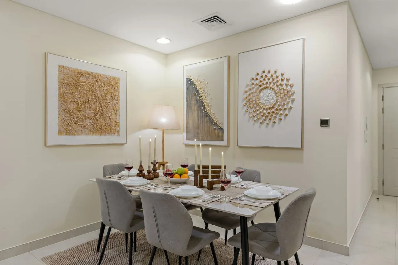 Un comedor con una mesa puesta bajo cuadros enmarcados.