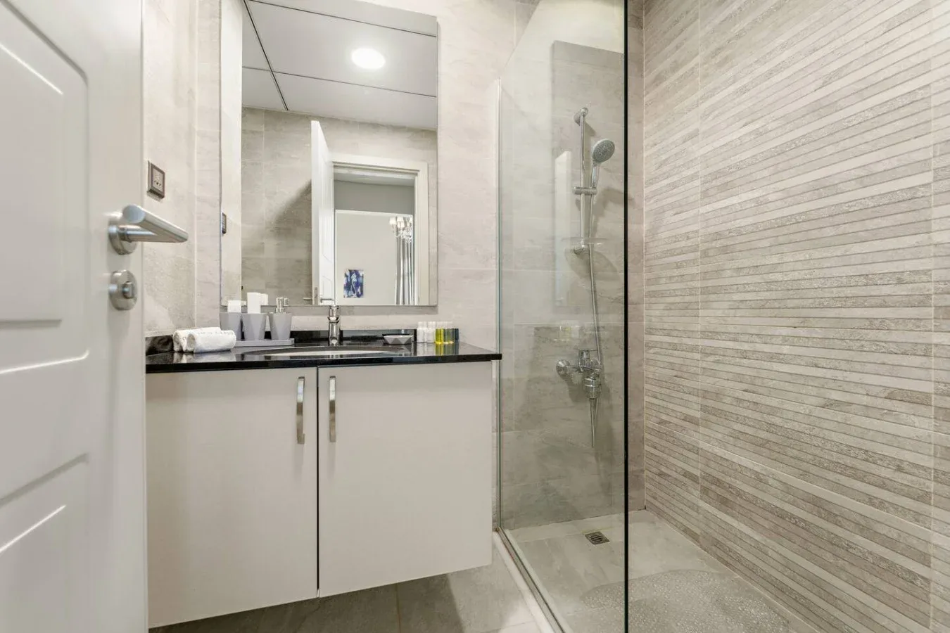 Un baño con un tocador y una ducha con mampara de vidrio.
