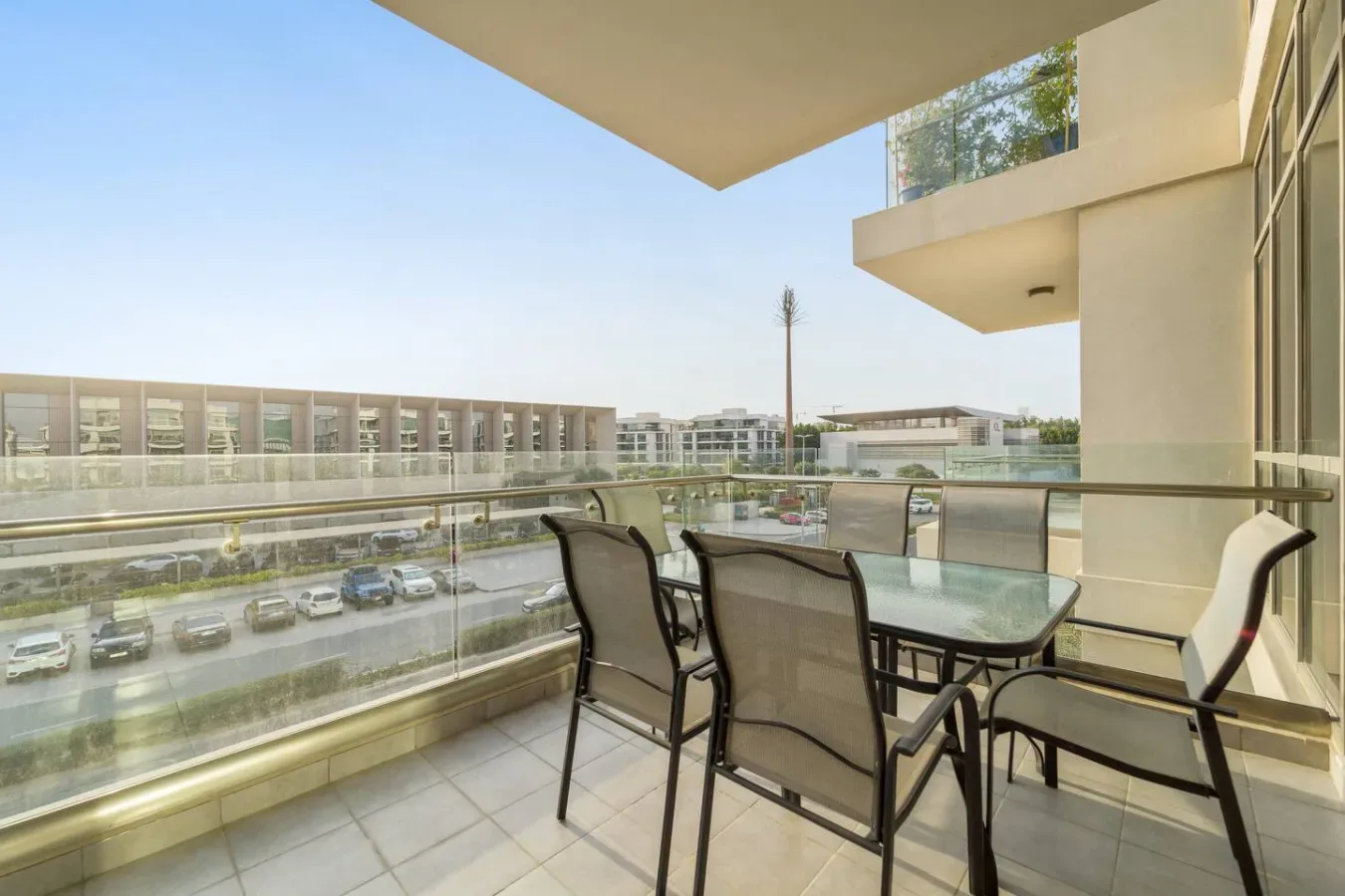 Una zona de estar en un balcón con mesa de vidrio da a edificios cercanos.
