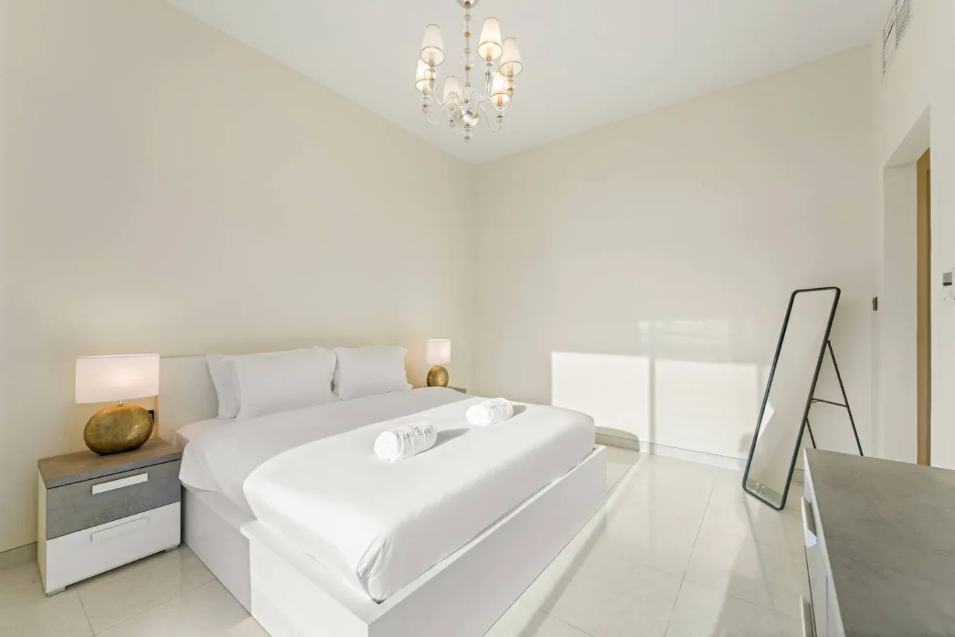 Un dormitorio luminoso con una cama bien hecha y una lámpara de noche.