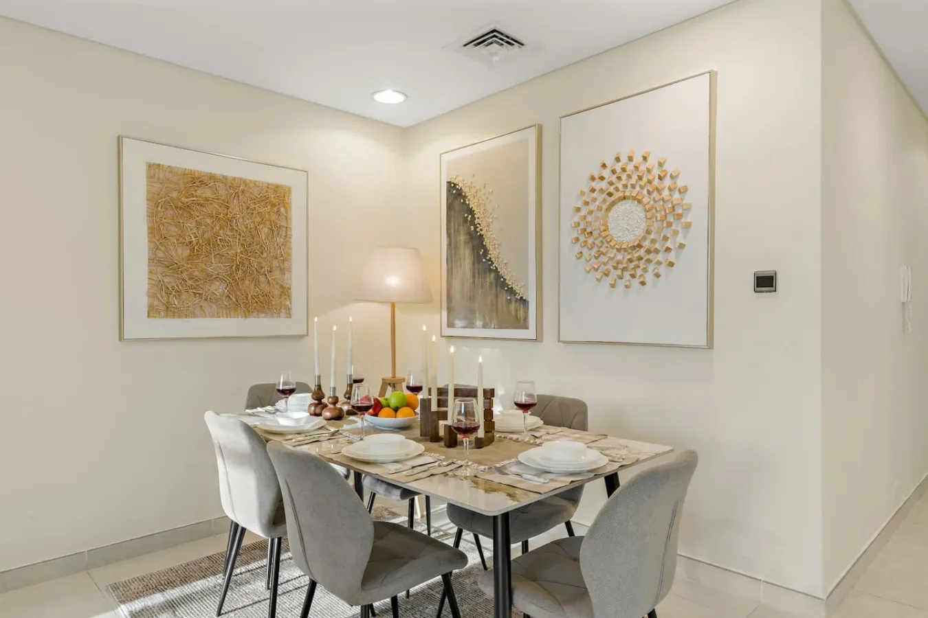 Un comedor con la mesa puesta bajo cuadros enmarcados.