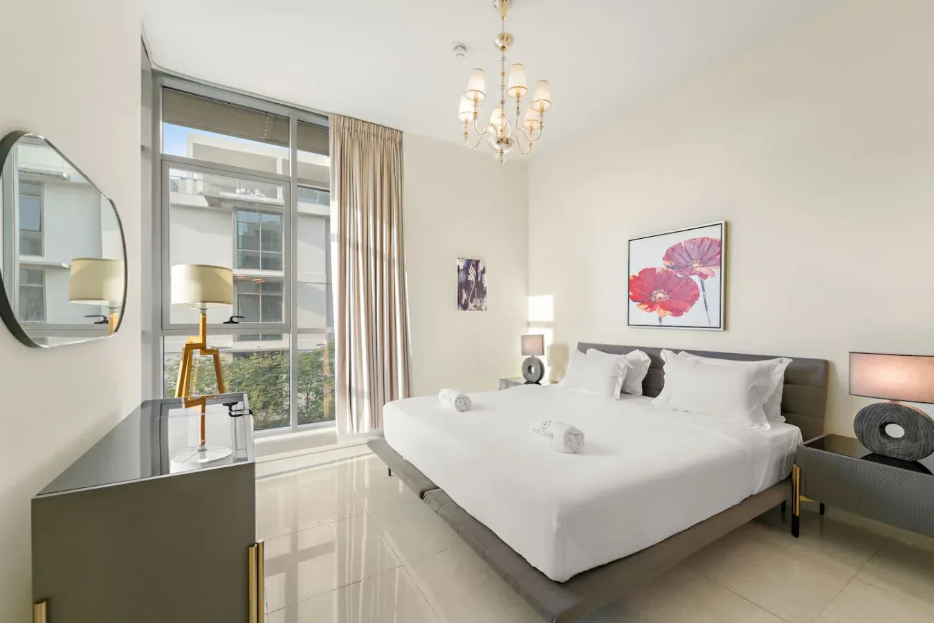 Un dormitorio luminoso con una cama grande, ventanales y arte floral en la pared.