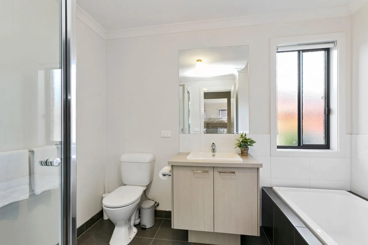 A bathroom with a vanity, toilet, and bathtub.