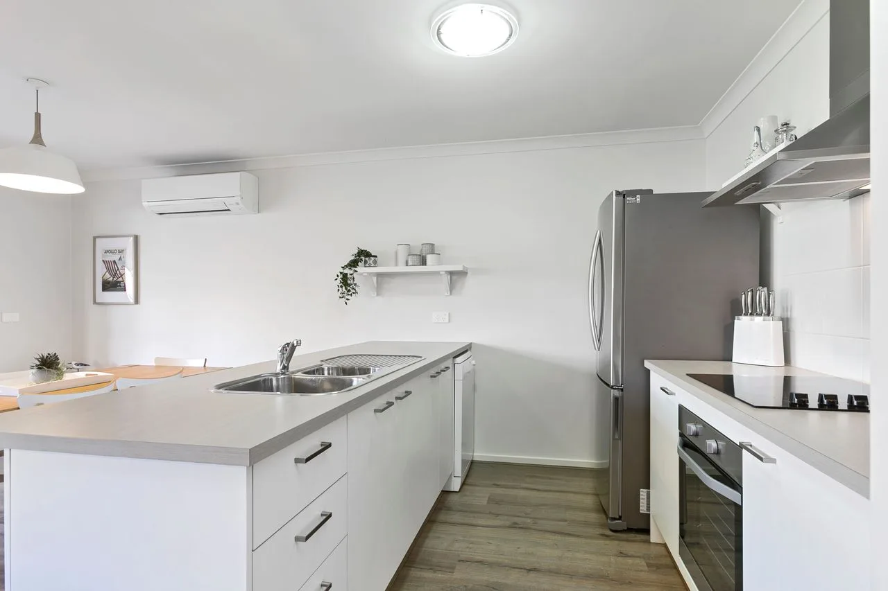 A bright modern kitchen with a central island and stainless steel appliances.