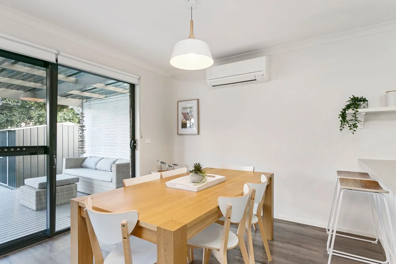 A bright dining area with a wooden table and sliding glass doors opening onto a patio.