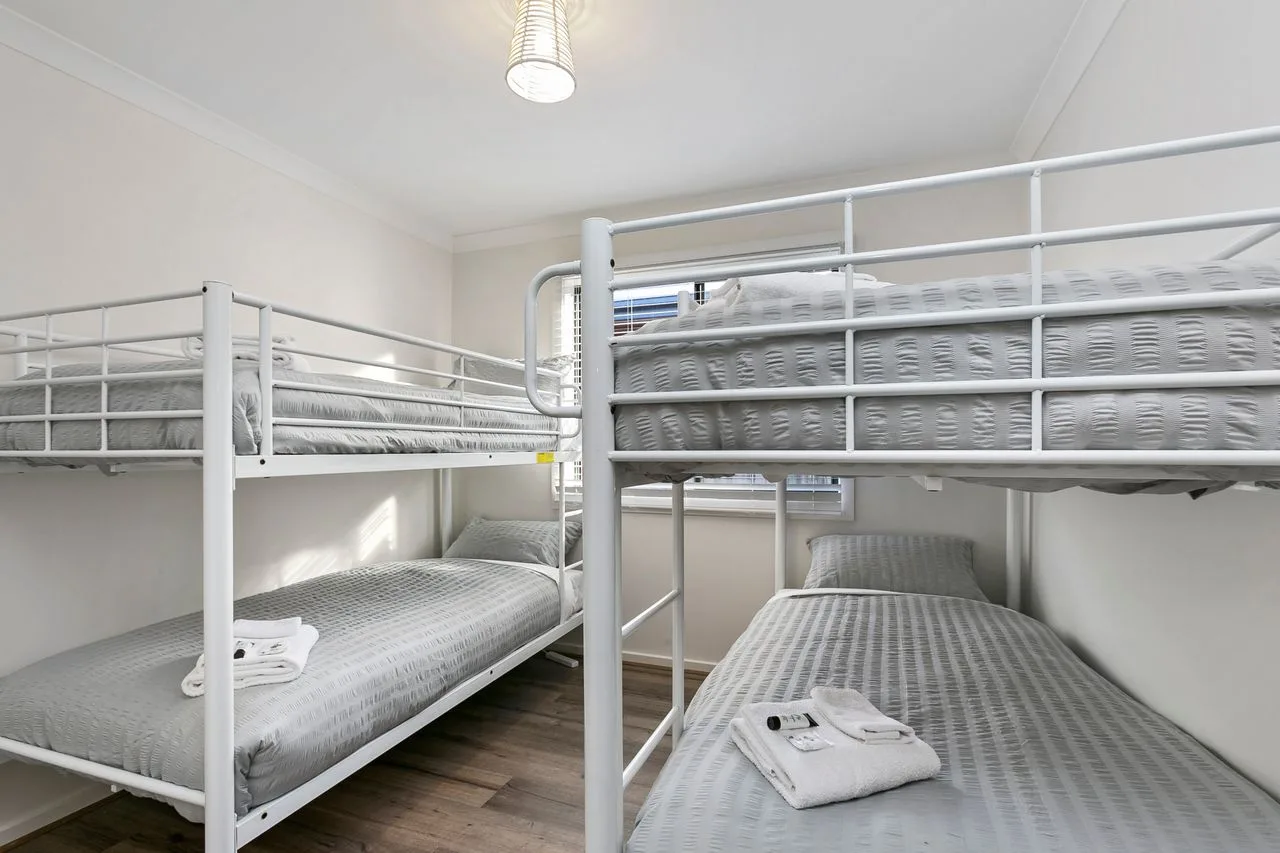A bright bedroom with bunk beds and neatly made bedding.