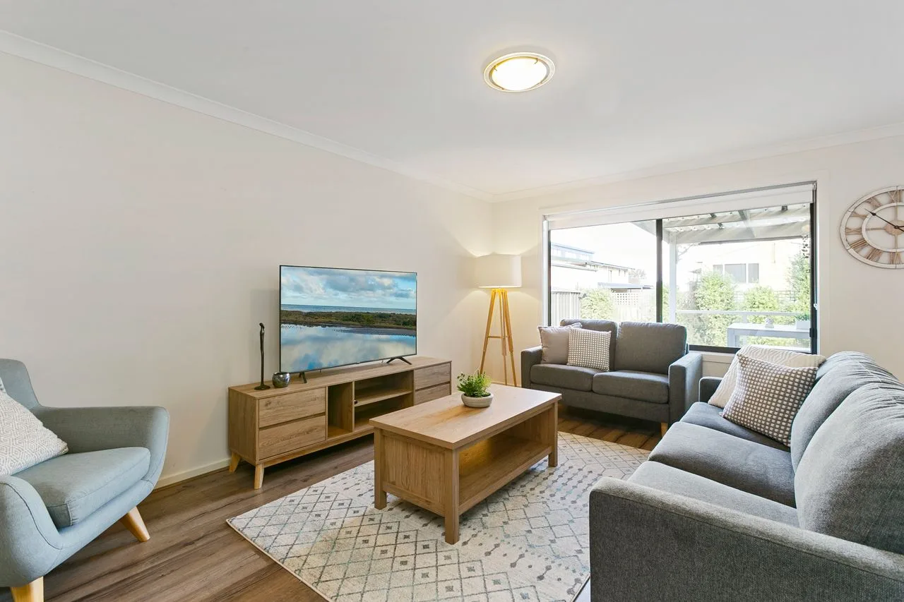 A living room with seating arranged around a wooden coffee table and television.