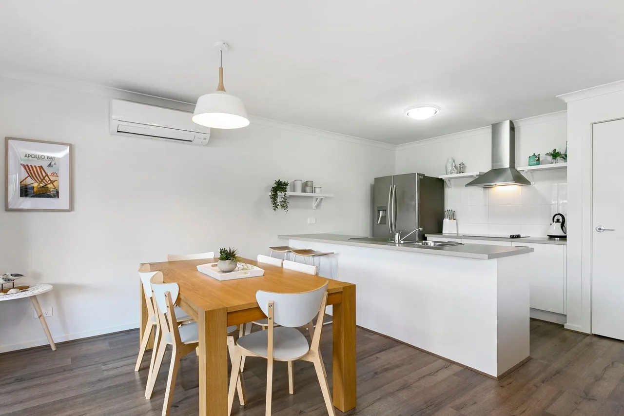 A bright open-plan kitchen and dining area with a wooden table.