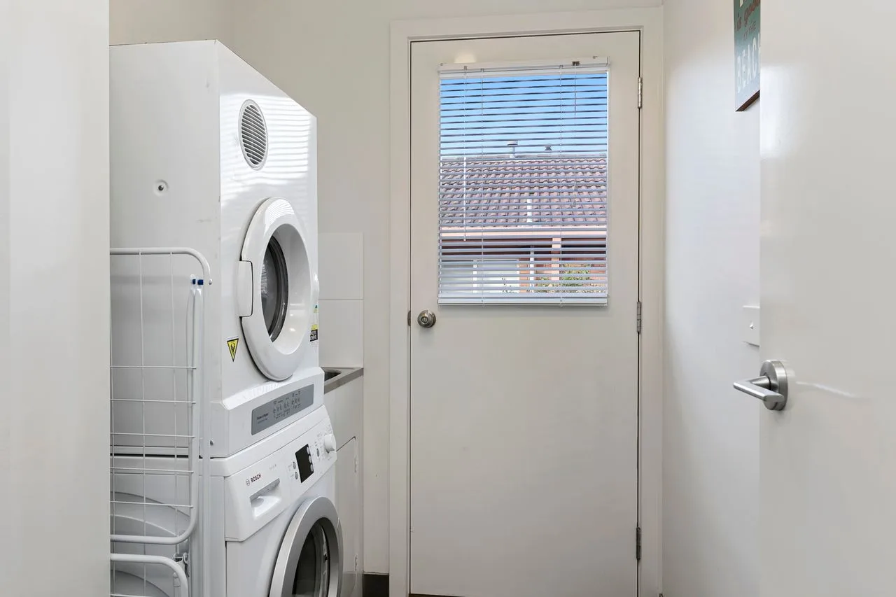 A laundry area with stacked laundry machines beside a door.