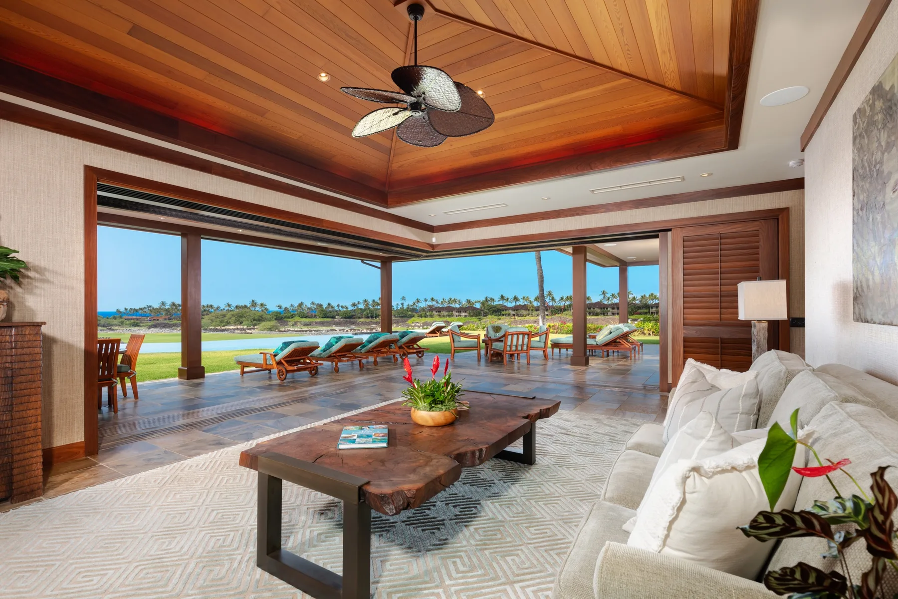 A bright lounge opens onto a terrace with seating and a view of the water.