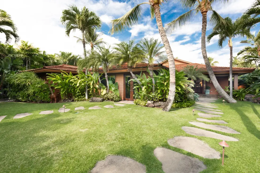 A landscaped garden with palm trees and a stepping-stone path in front of a low building.