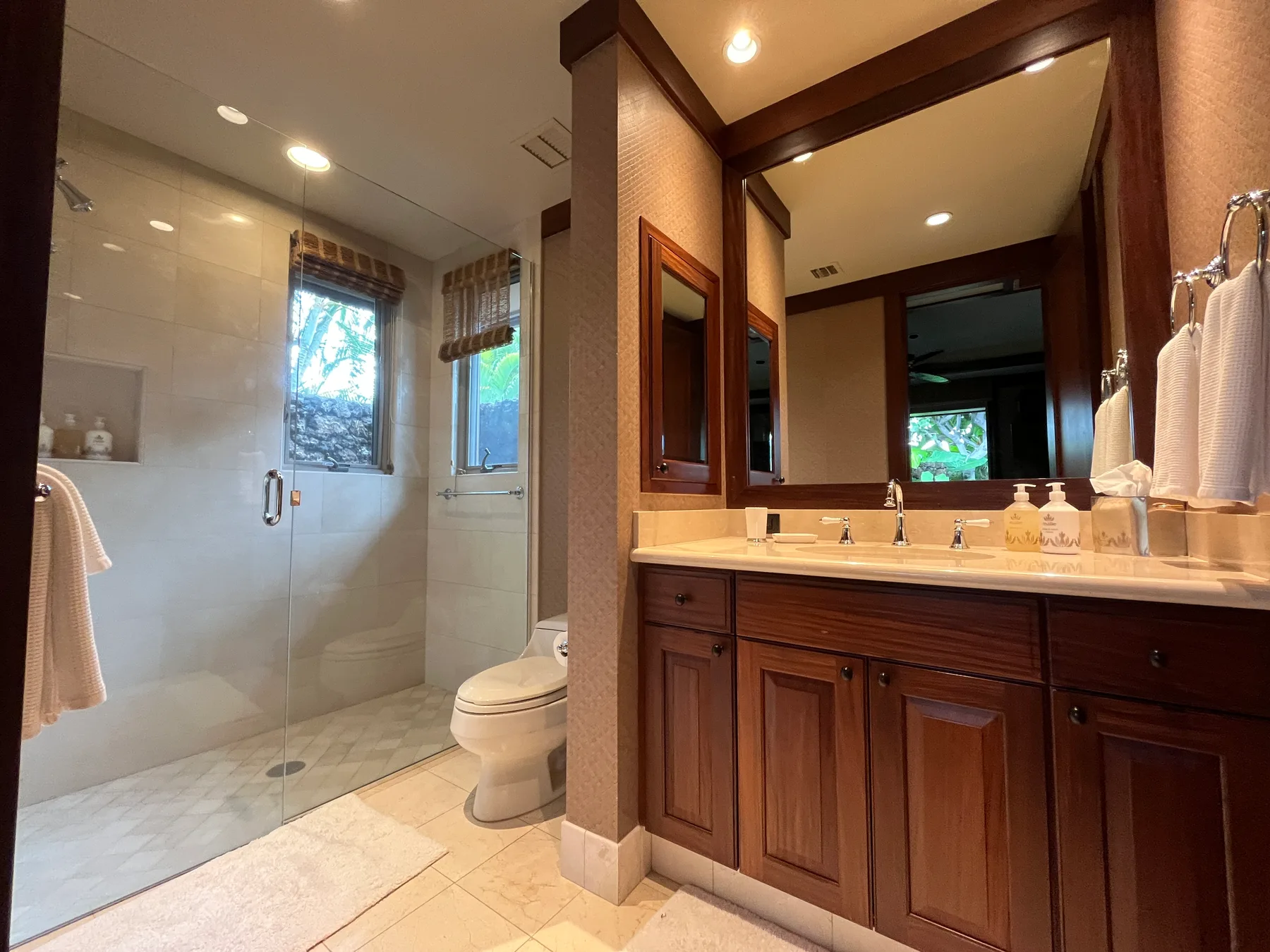 A bathroom with a glass shower and a wood vanity.