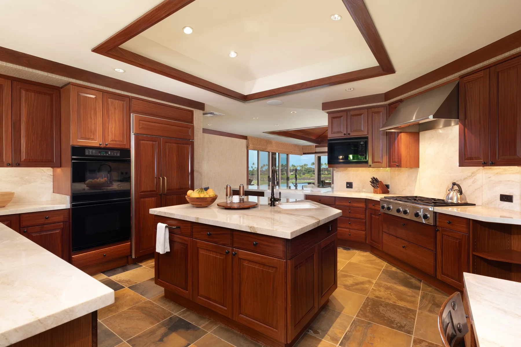 A spacious kitchen with dark wood cabinetry, stone counters, and a central island.