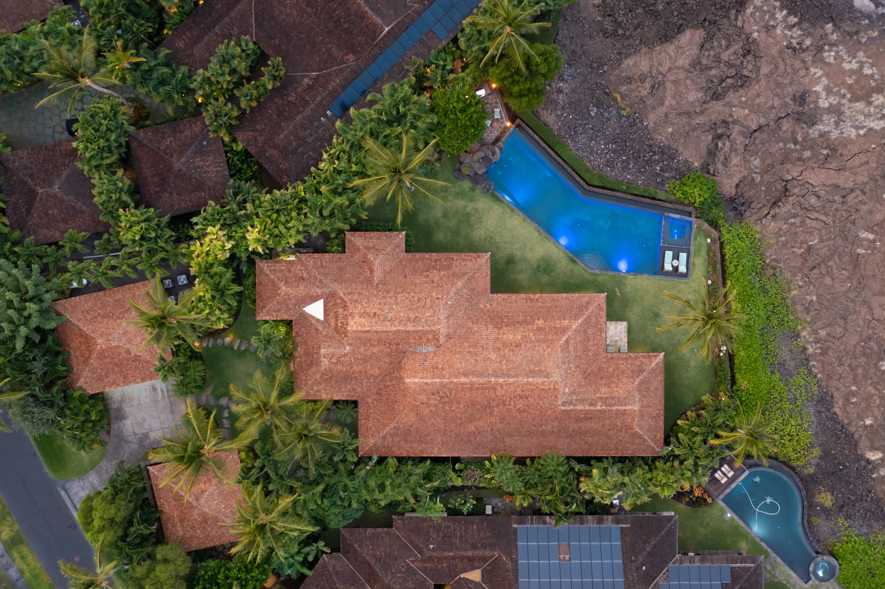 An aerial view of a landscaped property with several red-roofed buildings and a swimming pool.