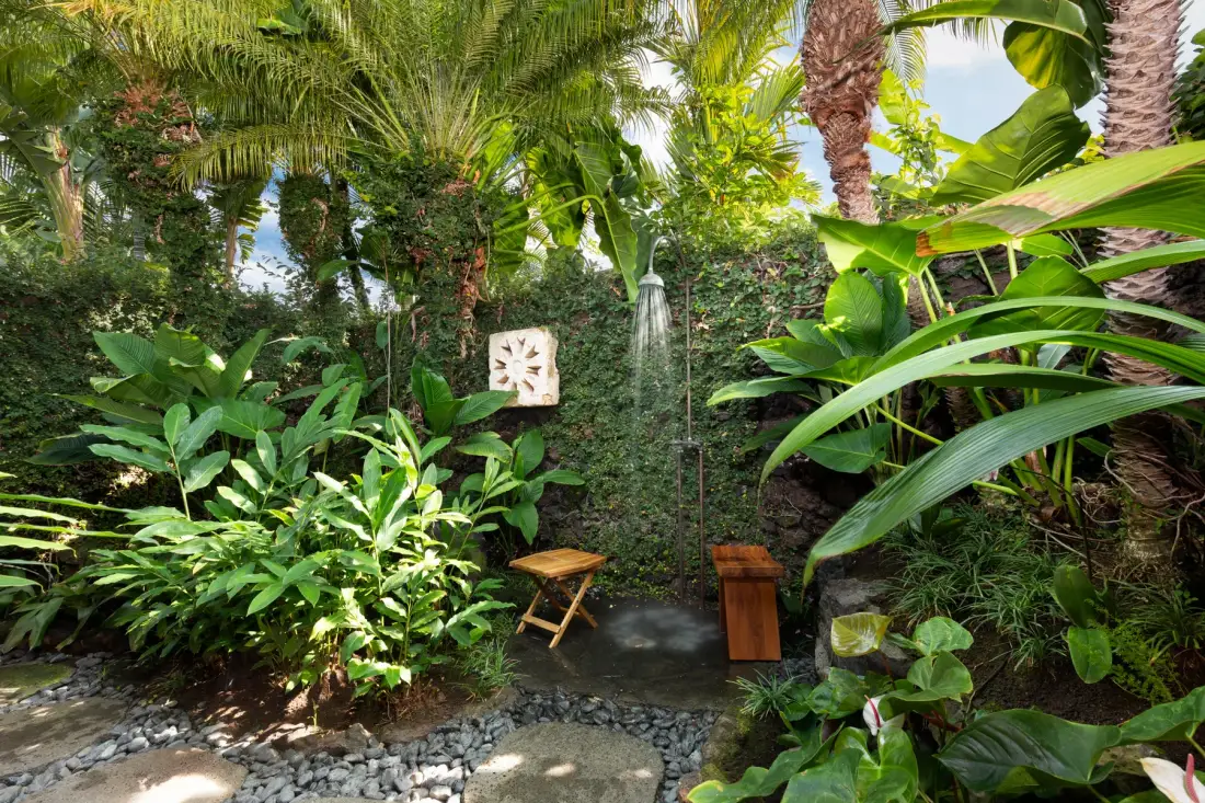 A garden shower is surrounded by dense tropical greenery.