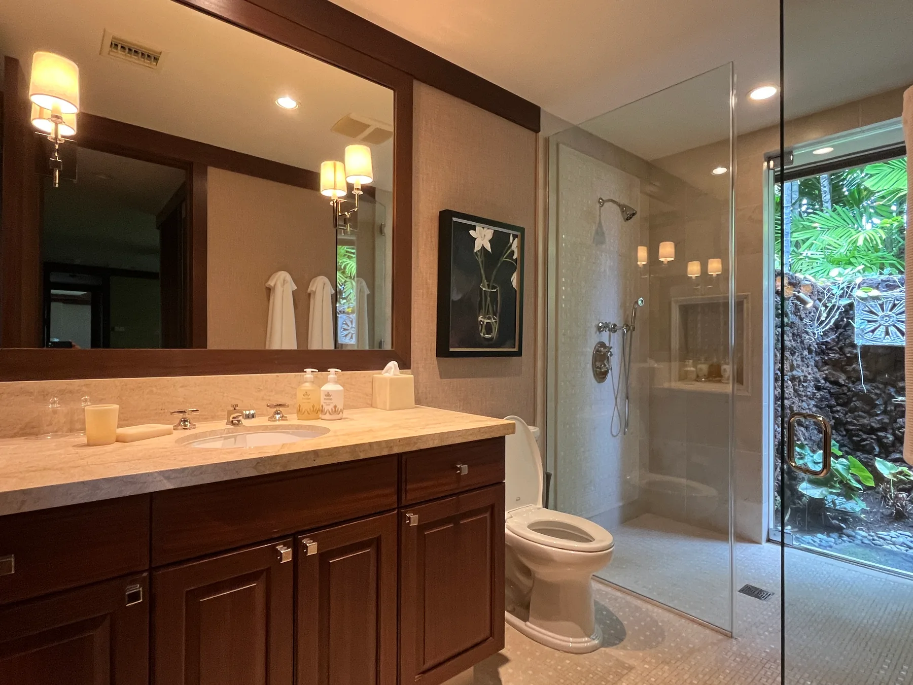 A bathroom with a long vanity, a toilet, and a glass shower.