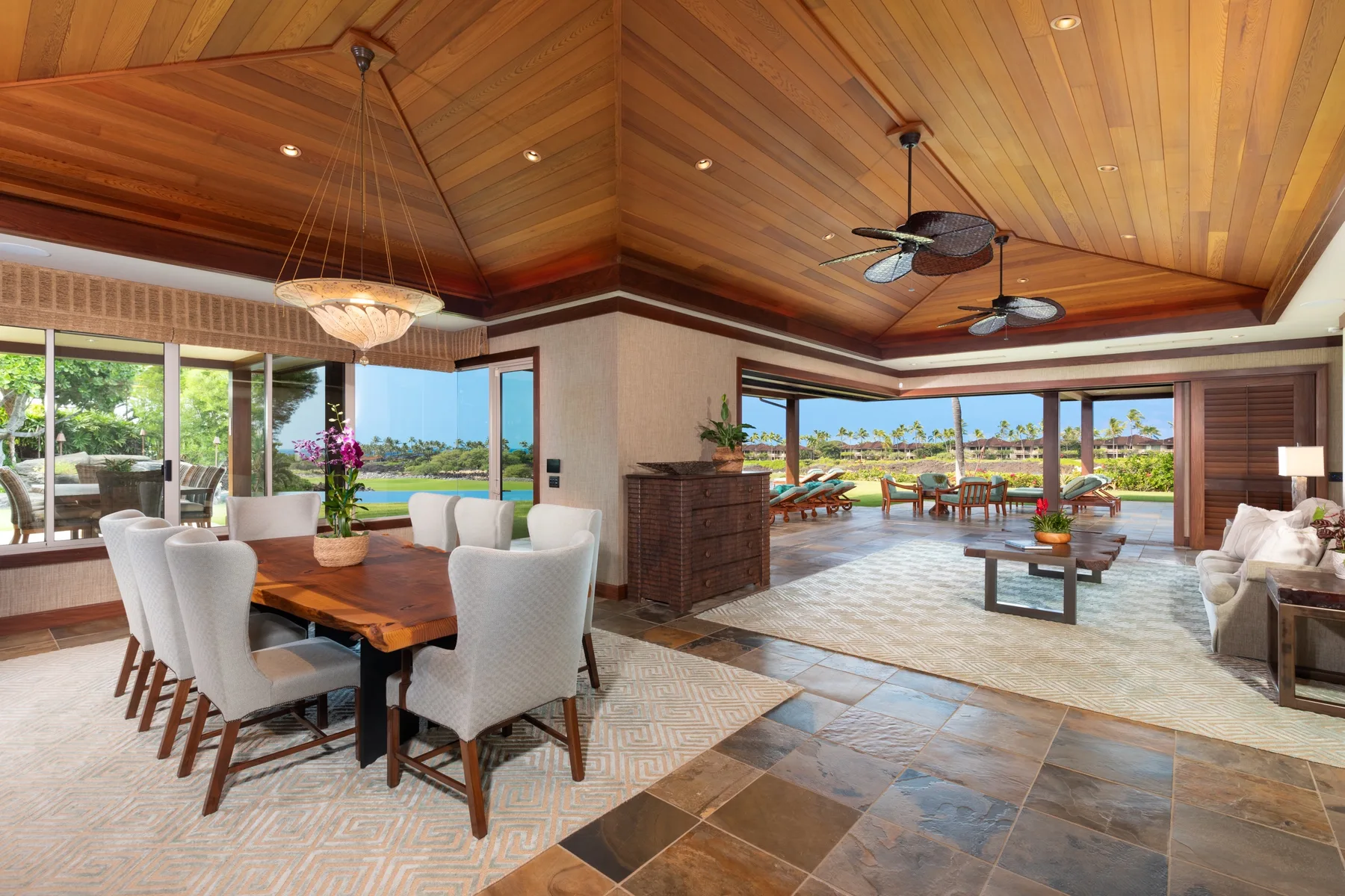 A spacious dining and living area opens onto large windows overlooking greenery and water.