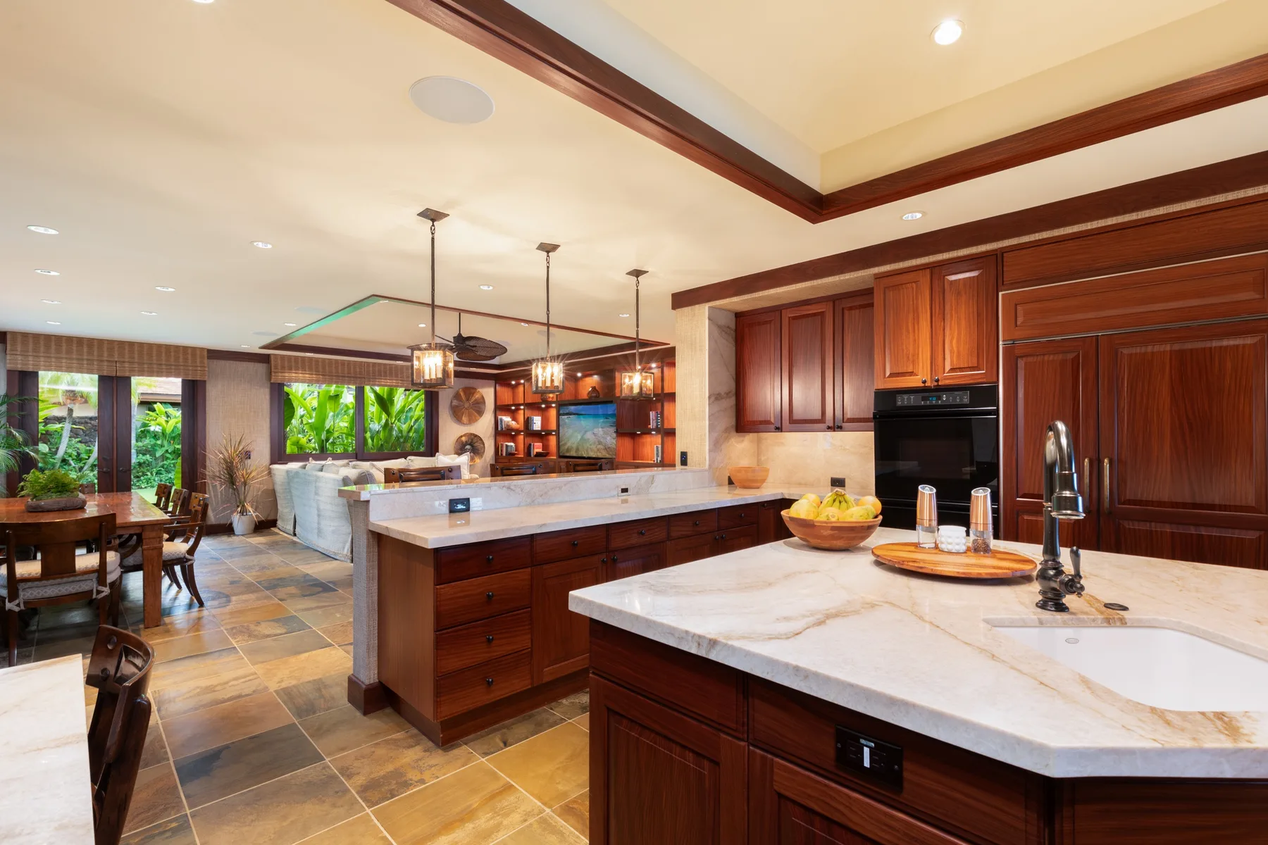A spacious kitchen with dark wood cabinetry, stone countertops, and a dining area.