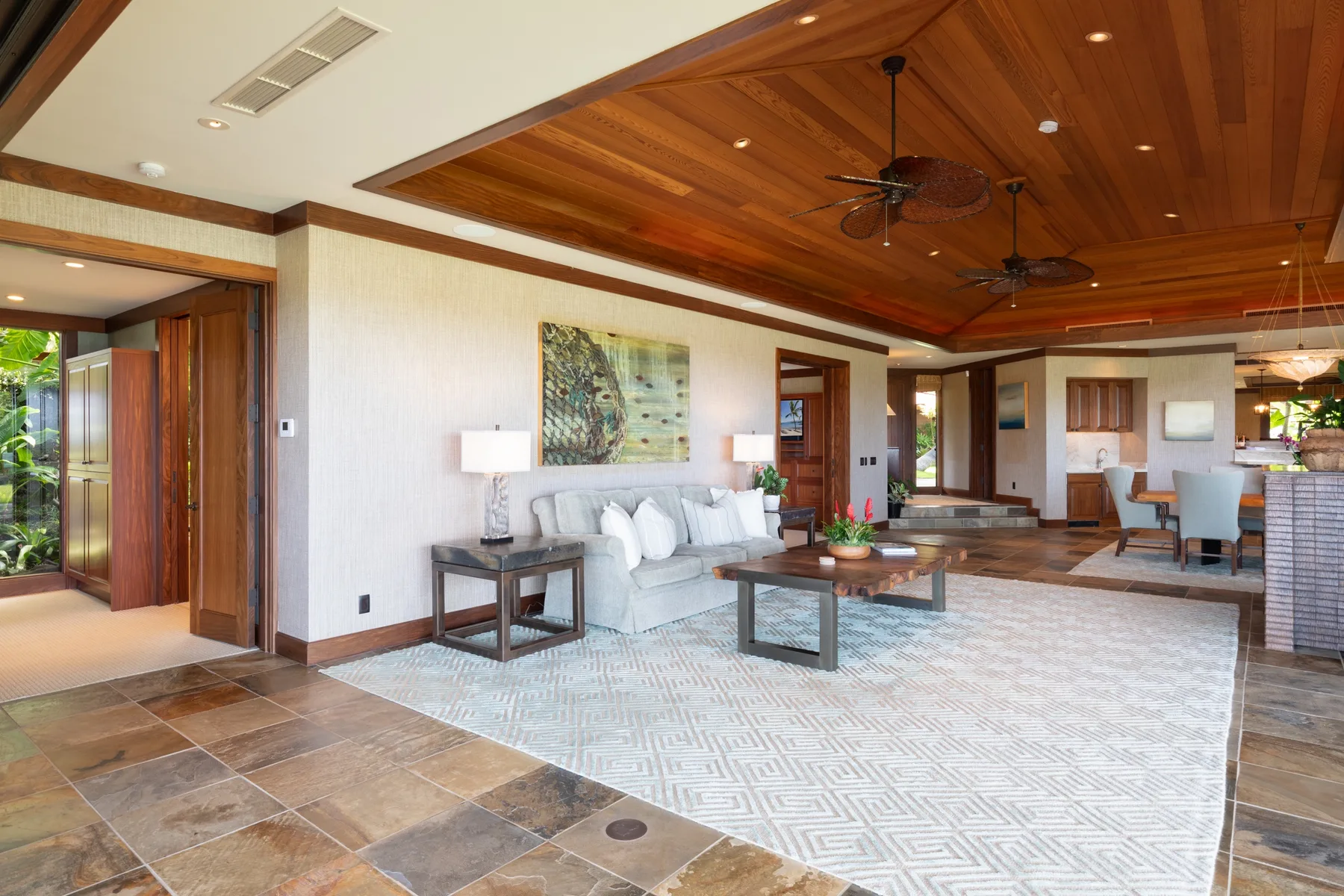 A spacious living area with seating, a coffee table, and a dining space beyond.