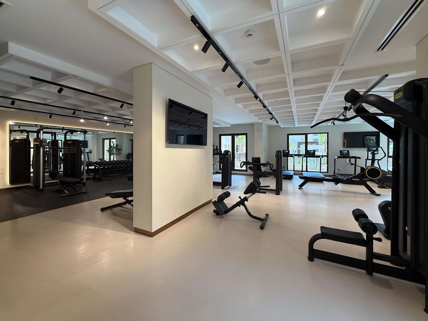 Una sala de ejercicio con máquinas y ventanas grandes.