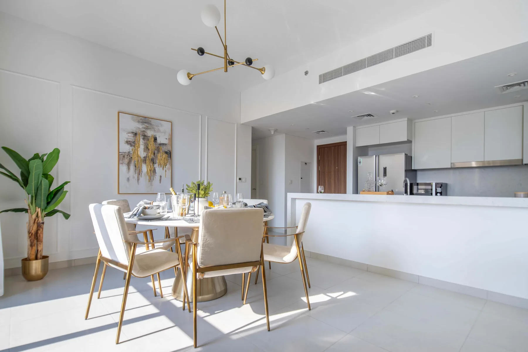 Un comedor luminoso con una mesa y asientos junto a una cocina abierta.