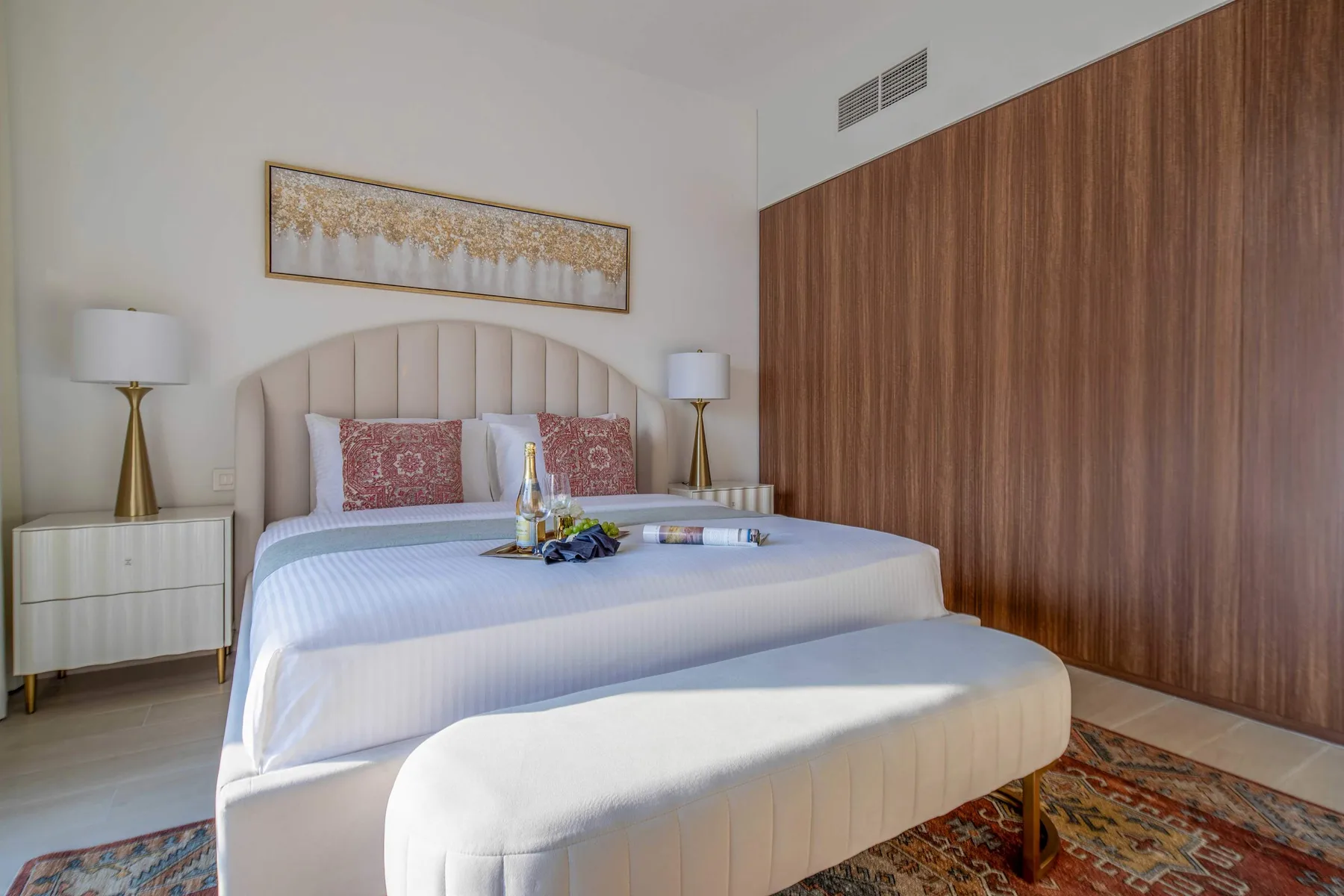 Un dormitorio con una cama grande, mesitas de noche y una pared revestida de madera.