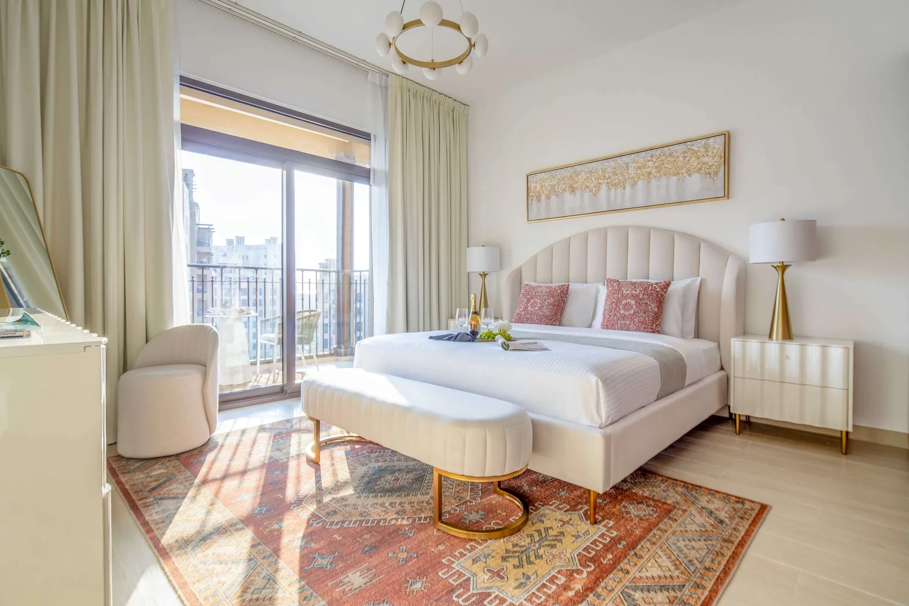Un dormitorio luminoso con una cama, una alfombra estampada y ventanas altas.