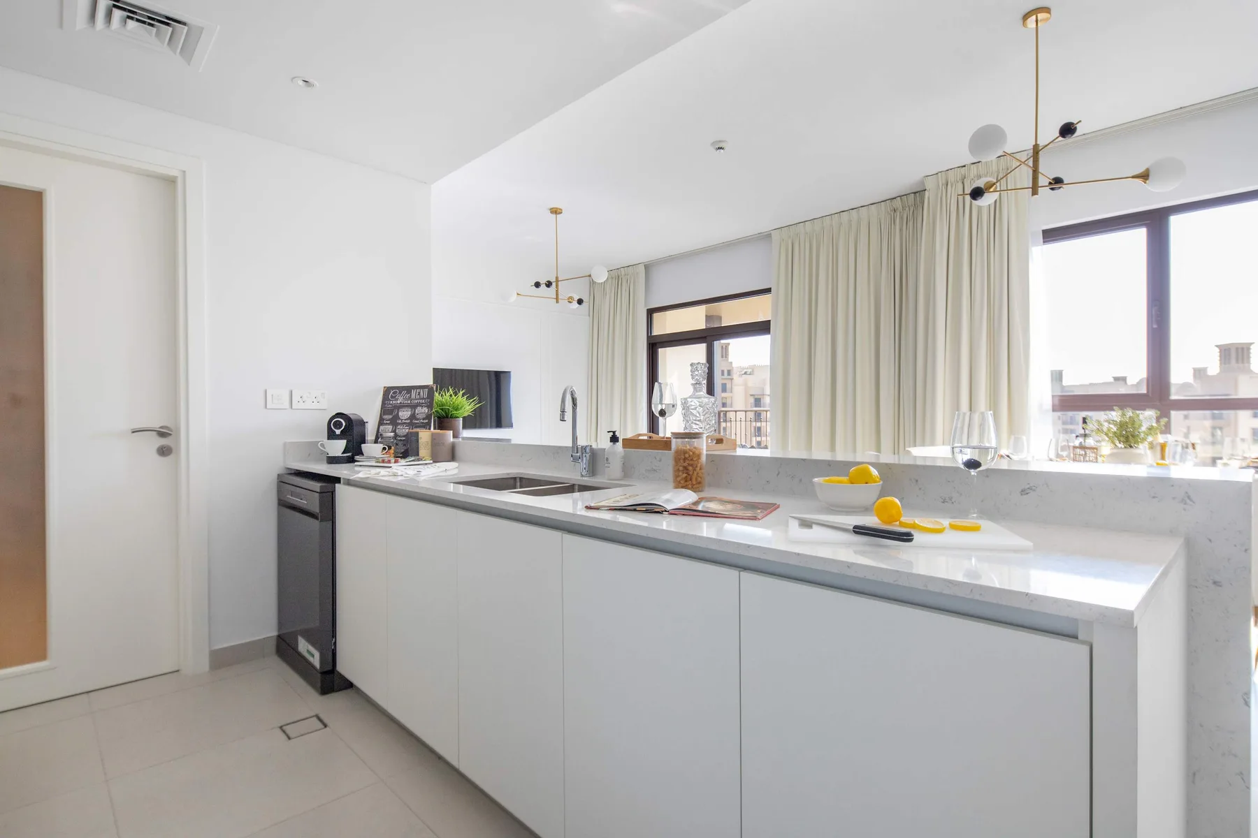 Una cocina moderna y luminosa con una isla larga y grandes ventanales.