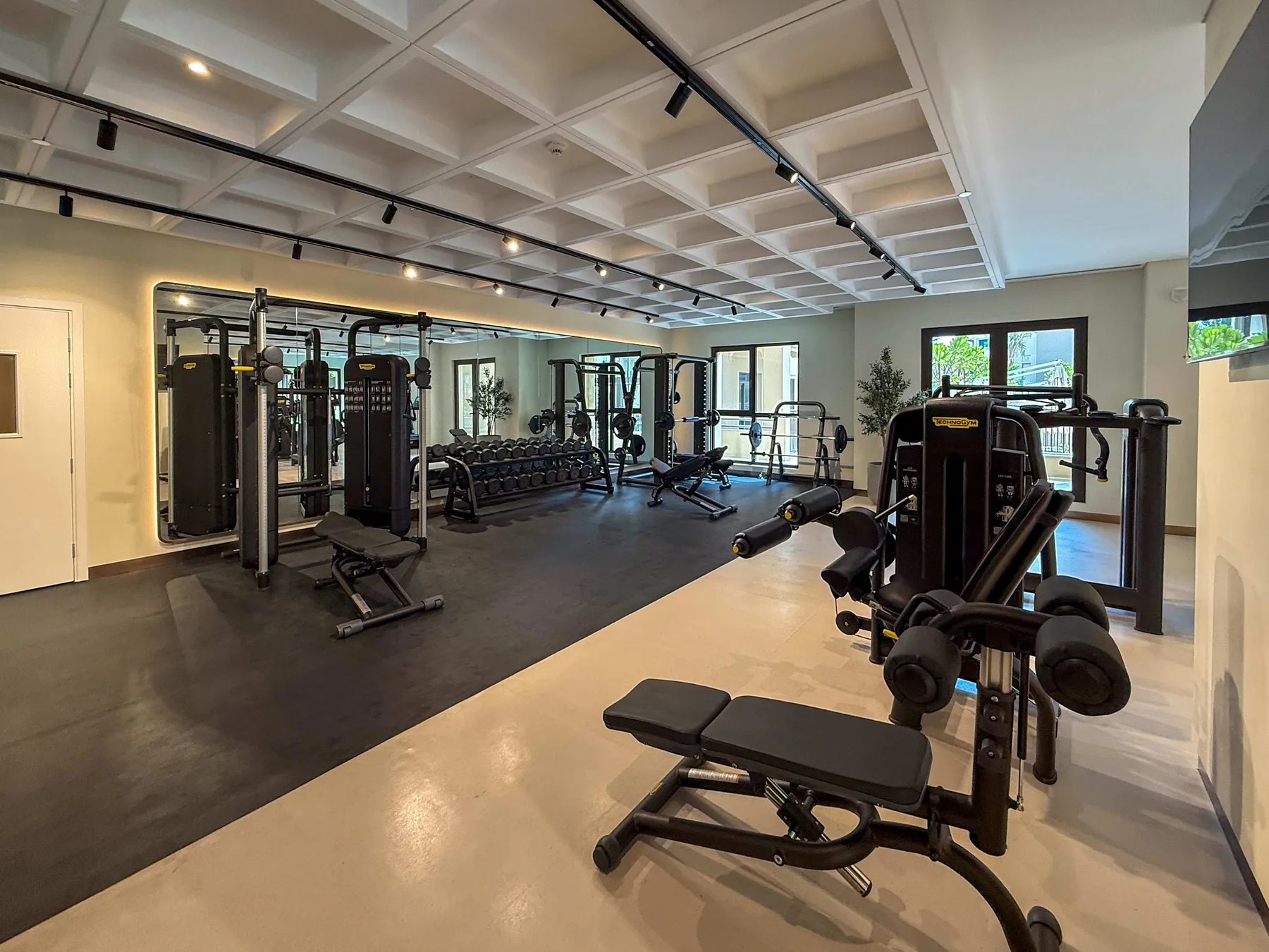 Un gimnasio amplio con máquinas de ejercicio y bancos distribuidos por la sala.