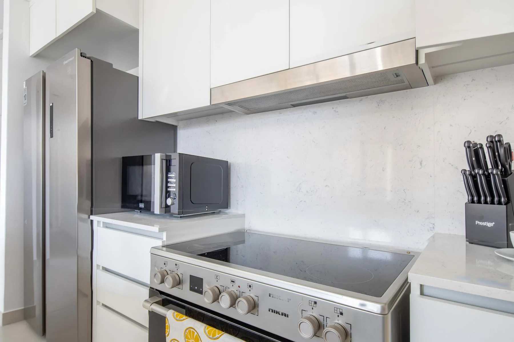 Una cocina moderna con electrodomésticos de acero inoxidable y gabinetes blancos.