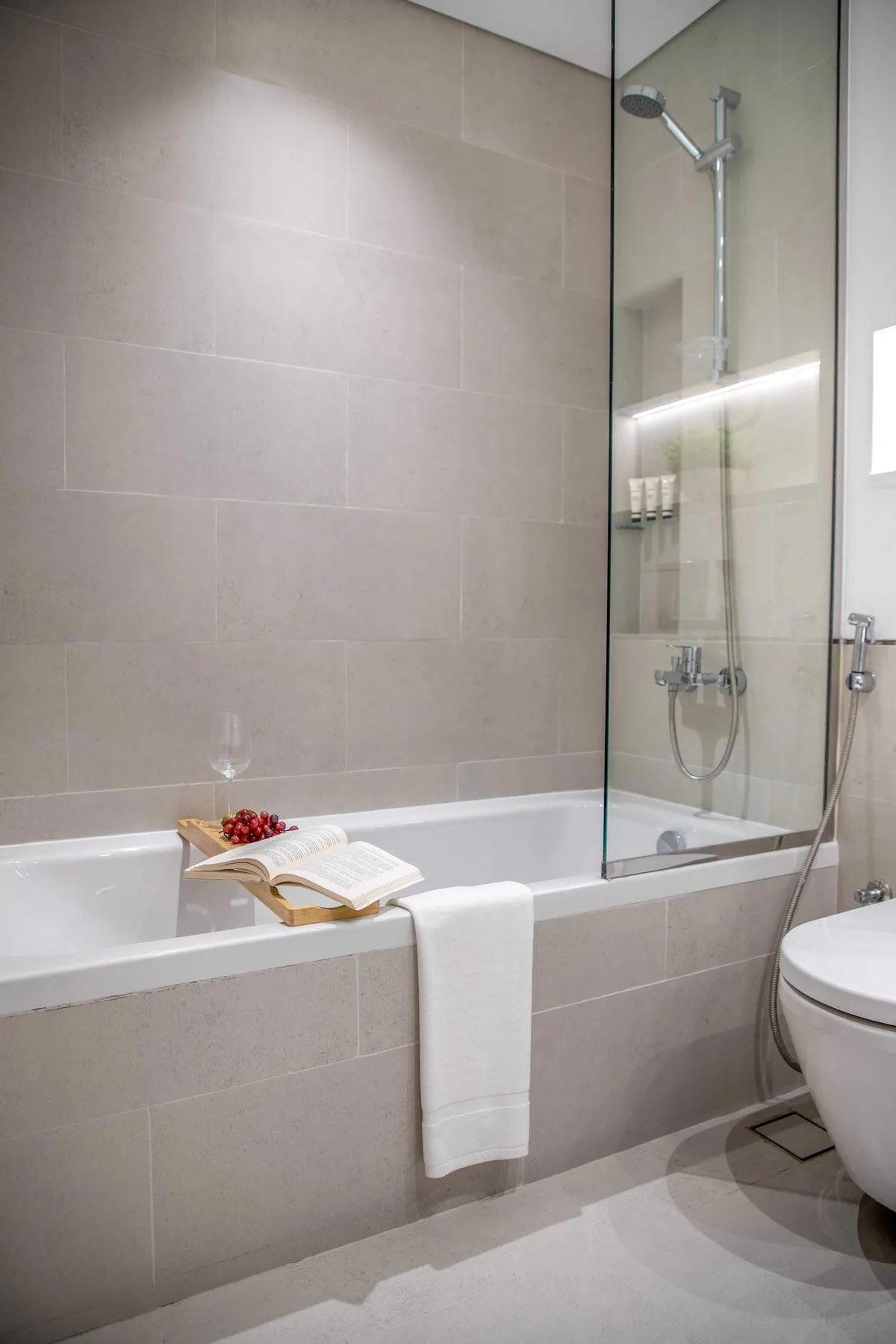 Un baño alicatado con bañera, mampara de vidrio y retrete.